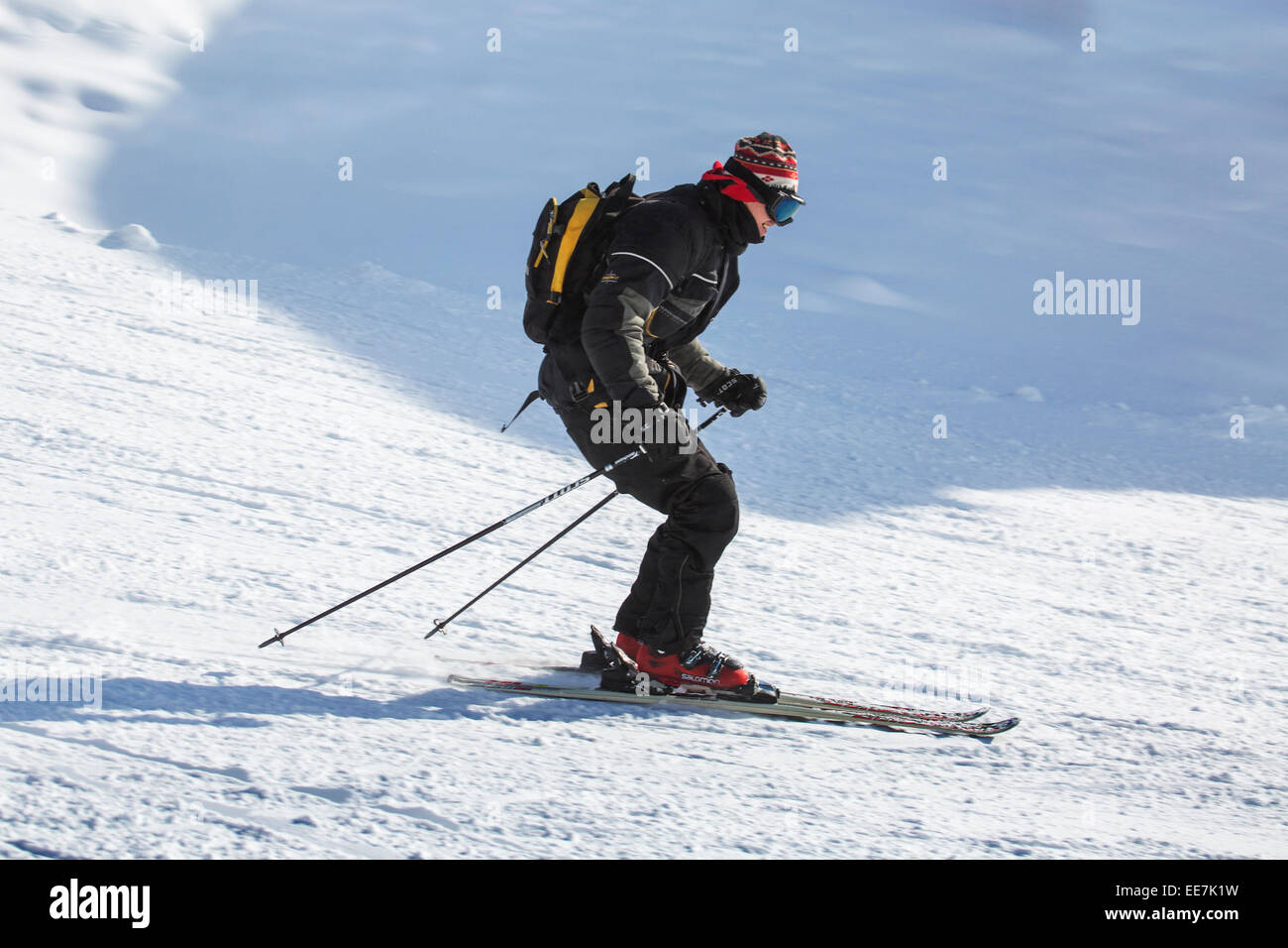Skifahrer mit Rucksack Skifahren auf der Piste im Wintersportort in den Alpen Stockfoto