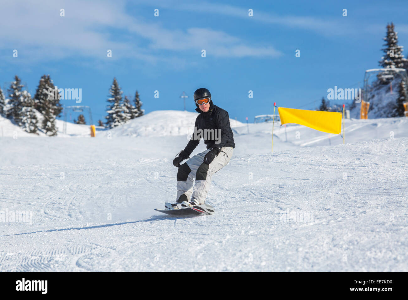 Snowboarder, Ski Helm absteigend Skipiste im Wintersportort in den Alpen Stockfoto