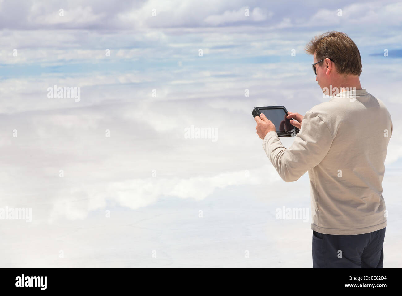 Mann arbeitet auf digital-Tablette in der Mitte des Sees Salar de Uyuini, Bolivien Stockfoto