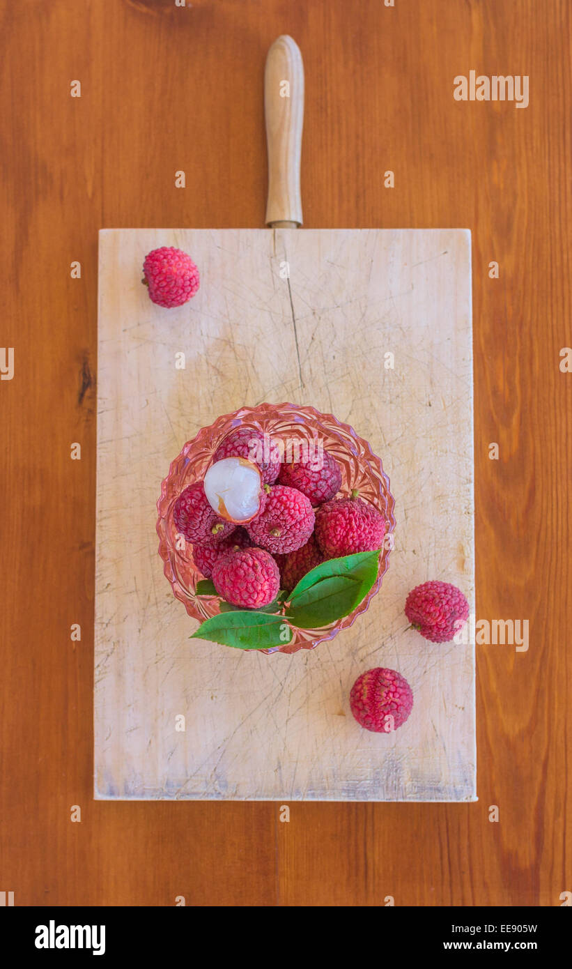 Draufsicht der schönen rosa Glasschüssel voll mit Litschis Obst und halb geschälte Litschi an der Spitze. Stockfoto