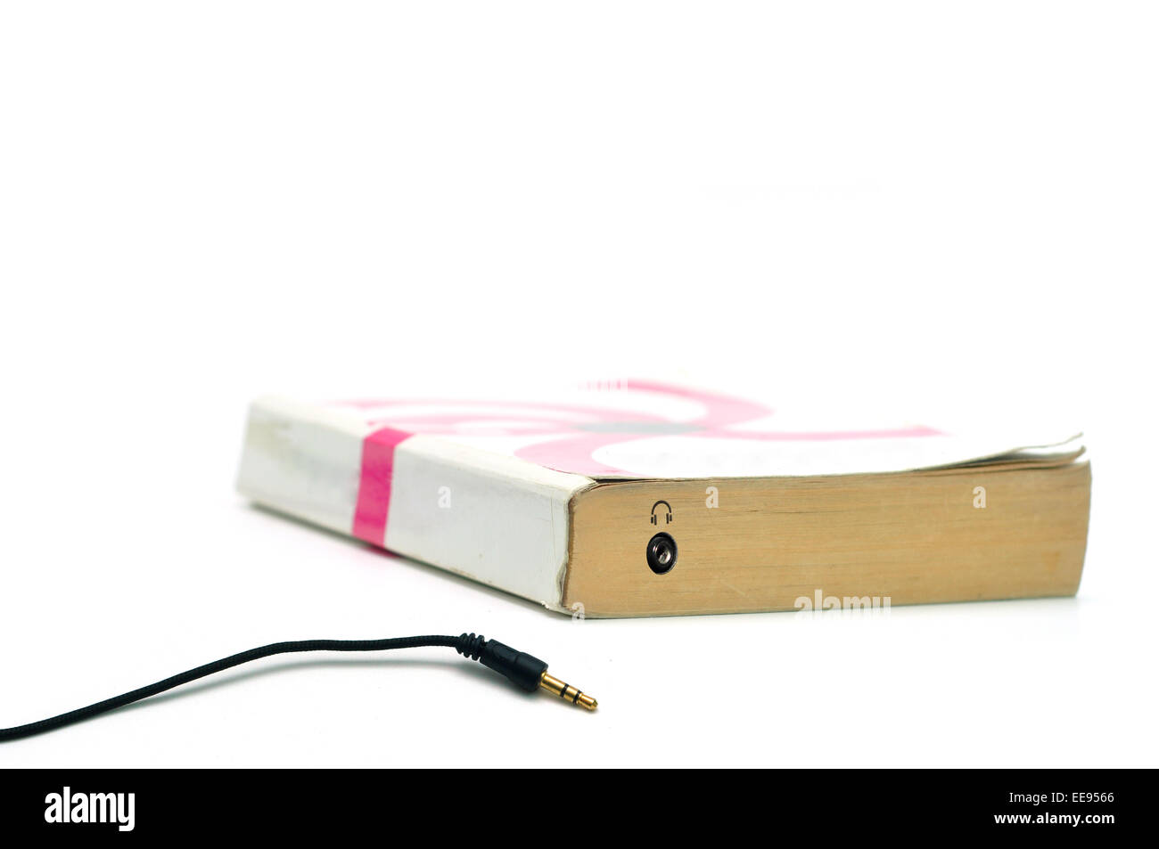 Kopfhörer-Buchse auf Buch isoliert auf weiss stellvertretend für Hörbuch-Konzept Stockfoto