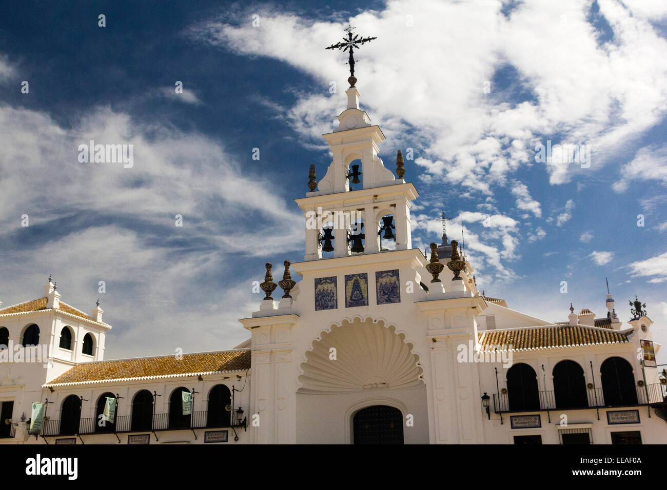 Glockenturm, Kruzifix und Tiled Roof die Eremitage von El Rocío gegen eine lebendige blauen Himmel mit Licht Cloud. Donana Nationalpark. Stockfoto