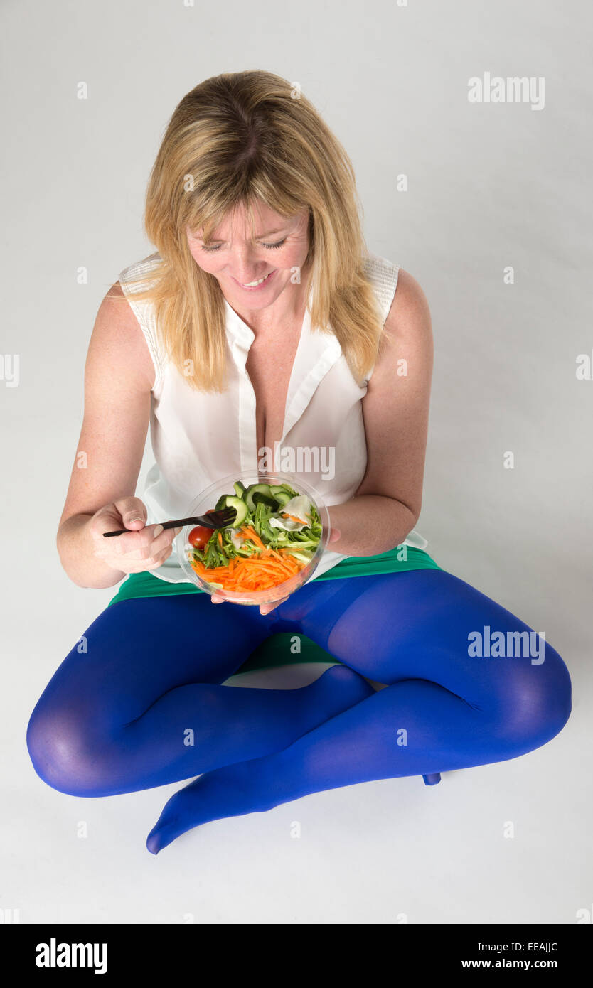 Beinigen Frau gesund essen ein Salat mit Karotten Salat Tomate und Gurke weiblichen sitzen gekreuzt Stockfoto