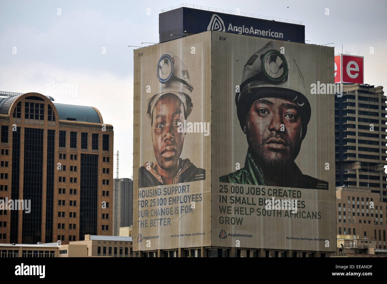 Die Gesichter der Bergleute auf einem Wolkenkratzer in der Innenstadt von Johannesburg betrachtet aus der Ferne. Stockfoto
