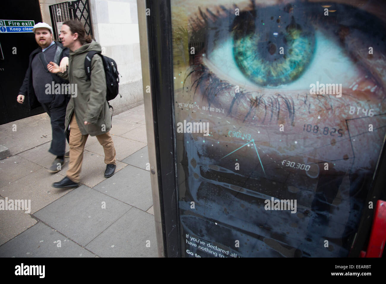 Ein blinder oder sehbehinderter Mensch geht vorbei an Big Brother wie Auge Blick aus einer Telefonzelle im Zentrum von London. Das groß angelegte Auge sieht, als ob sie Überwachung auf Passanten hält. VEREINIGTES KÖNIGREICH. Stockfoto