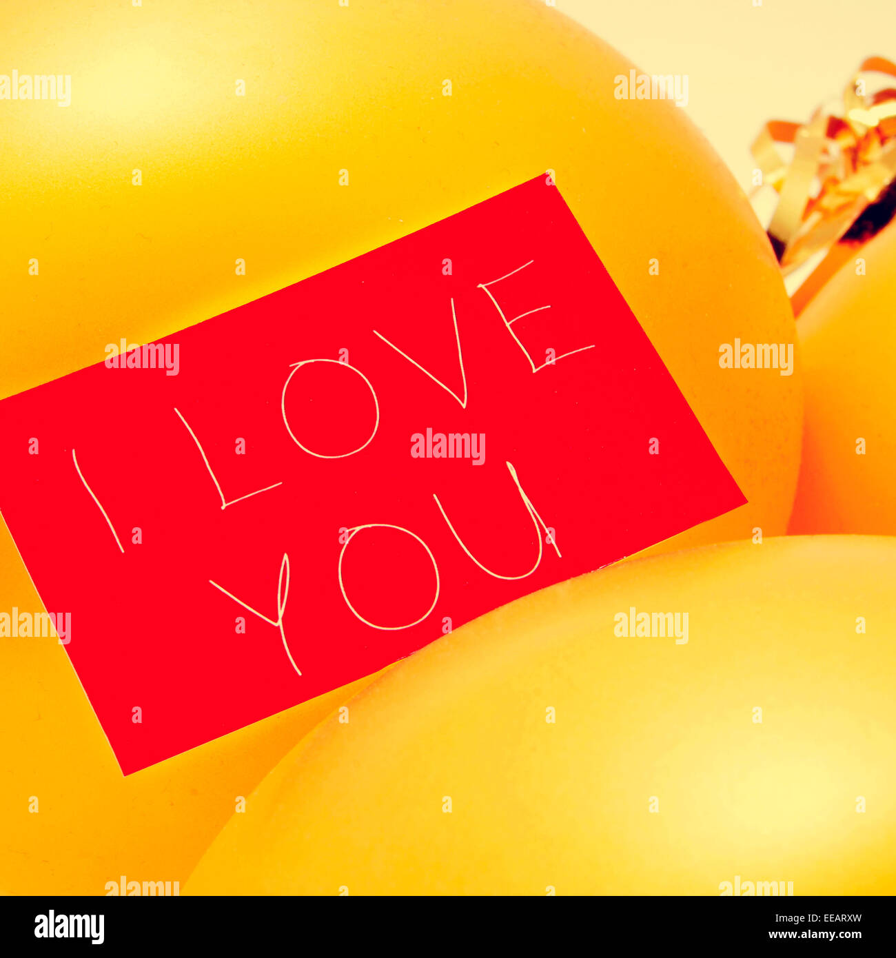 der Text ich liebe dich in einem roten Schild auf eine Reihe von festlichen goldene Luftballons, mit einem Filtereffekt geschrieben Stockfoto