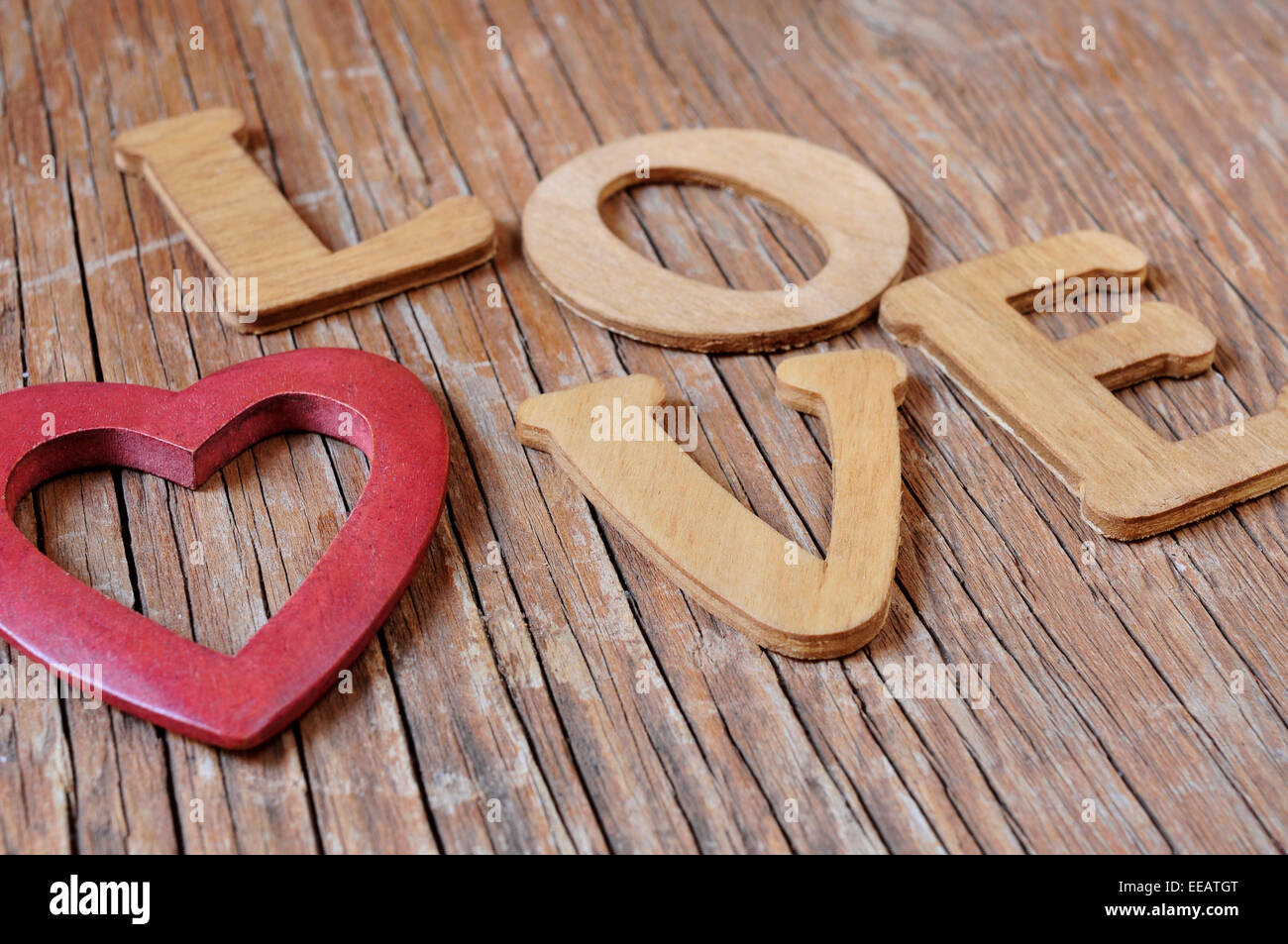 ein Herz aus Holz und hölzerne Buchstaben bilden das Wort Liebe auf einer rustikalen Holzoberfläche Stockfoto