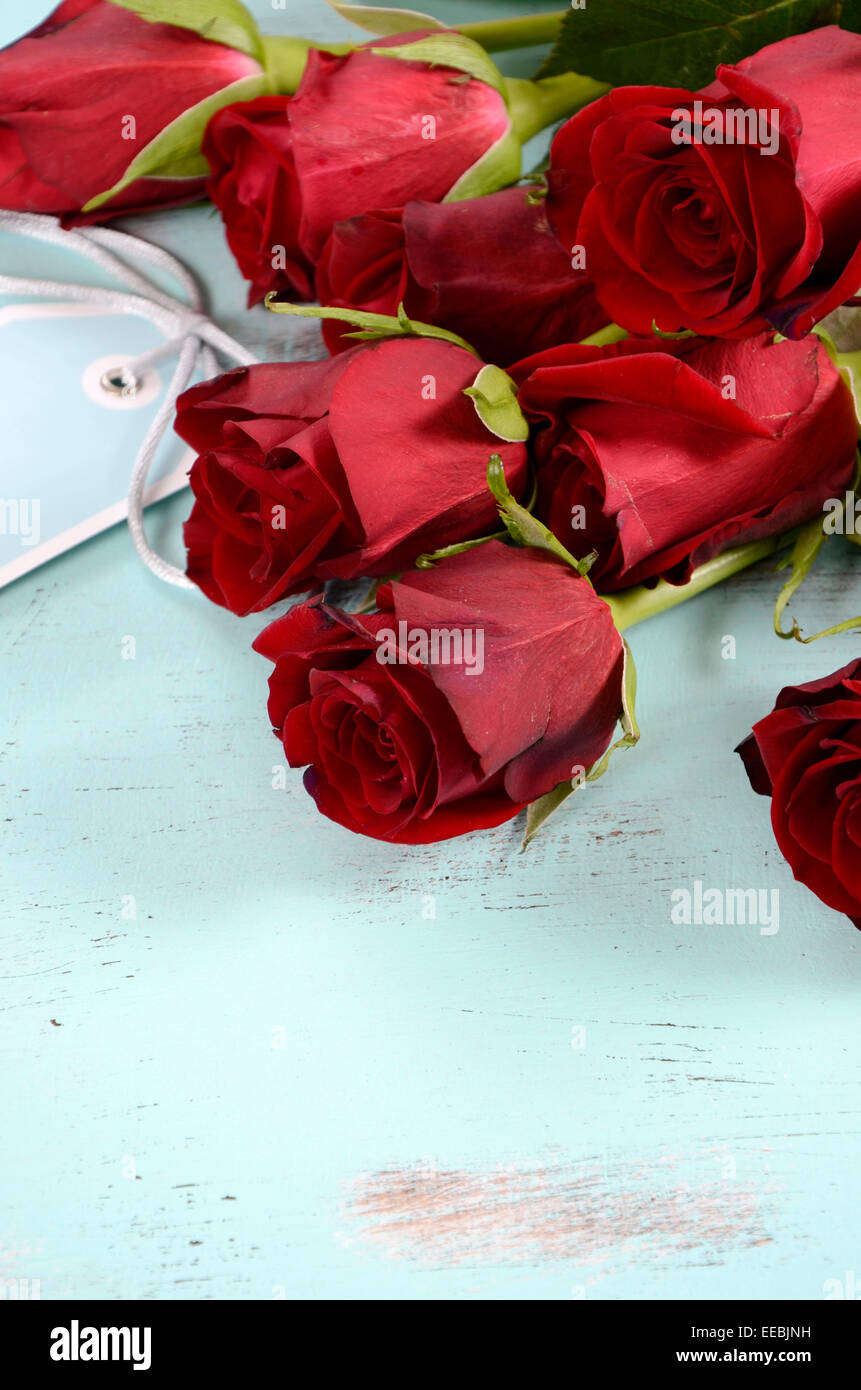 Vintage rote Rosen Geschenk für Valentinstag, Geburtstag oder besonderen Anlass auf blasse Aquablau recycelt notleidenden Holz Hintergrund. Stockfoto