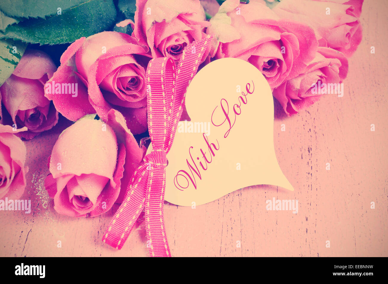 Happy Valentines Day Retro-Vintage-Stil rosa Rosen auf rosa Holz Hintergrund mit Herz Form Geschenk Tag und Sample Text. Stockfoto