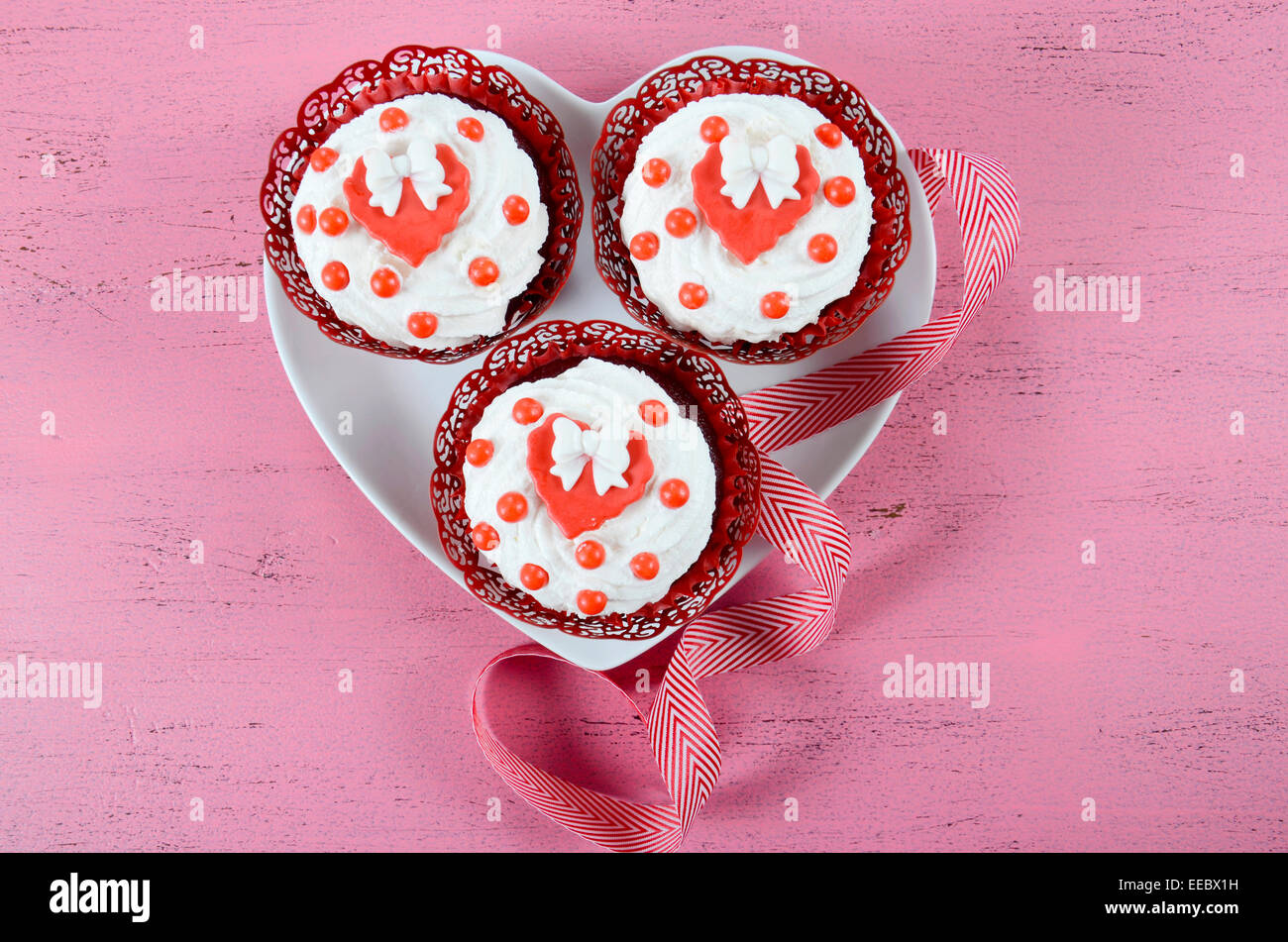 Happy Valentines Day Cupcakes mit Bögen über Kopf auf rosa Holz Hintergrund. Stockfoto
