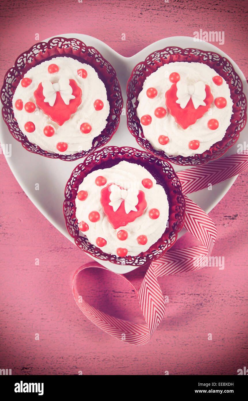 Retro-Filter Happy Valentines Day Cupcakes mit Bögen über Kopf auf rosa Holz Hintergrund. Stockfoto