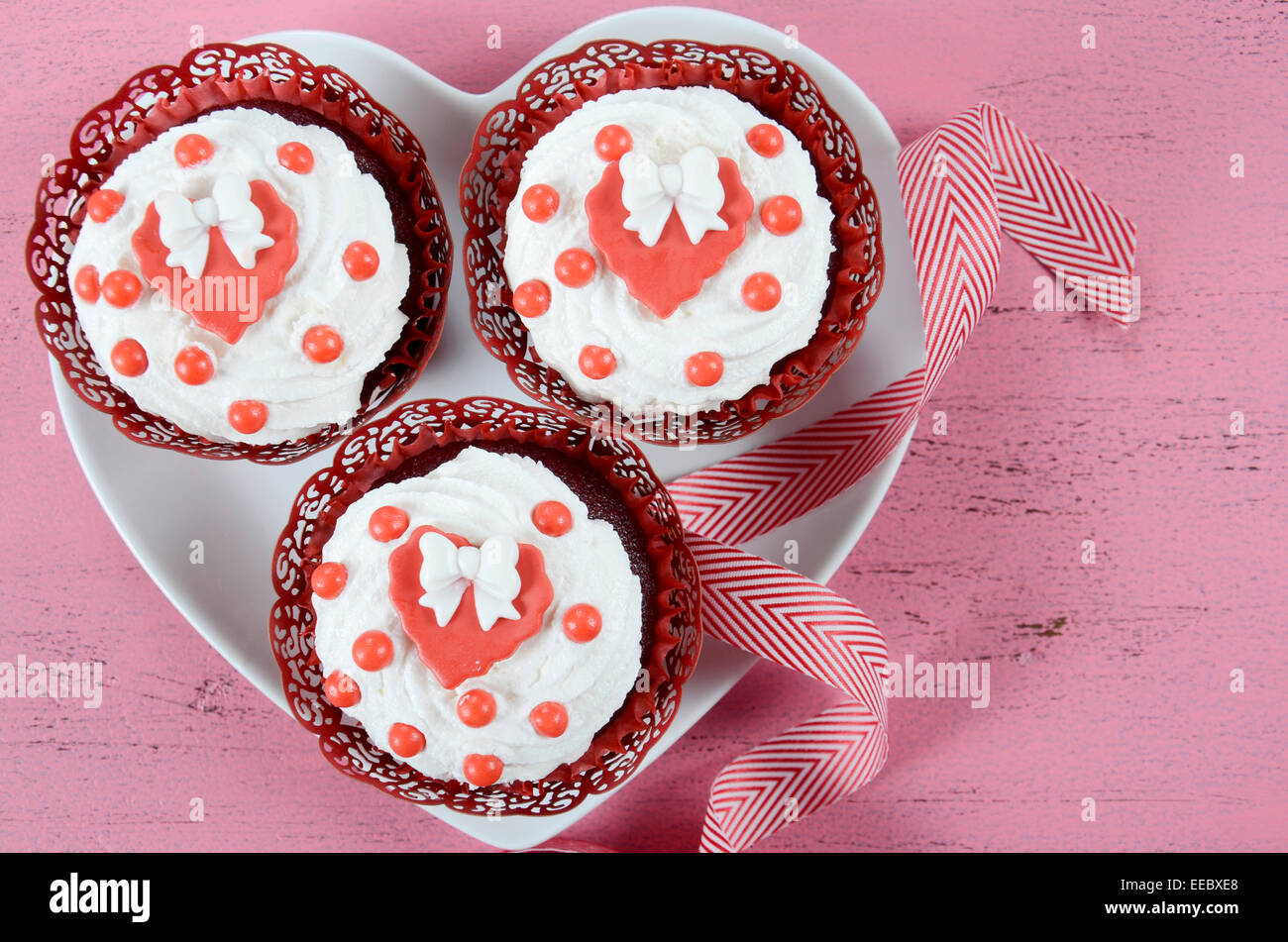 Happy Valentines Day Cupcakes mit Bögen über Kopf auf rosa Holz Hintergrund mit Textfreiraum. Stockfoto