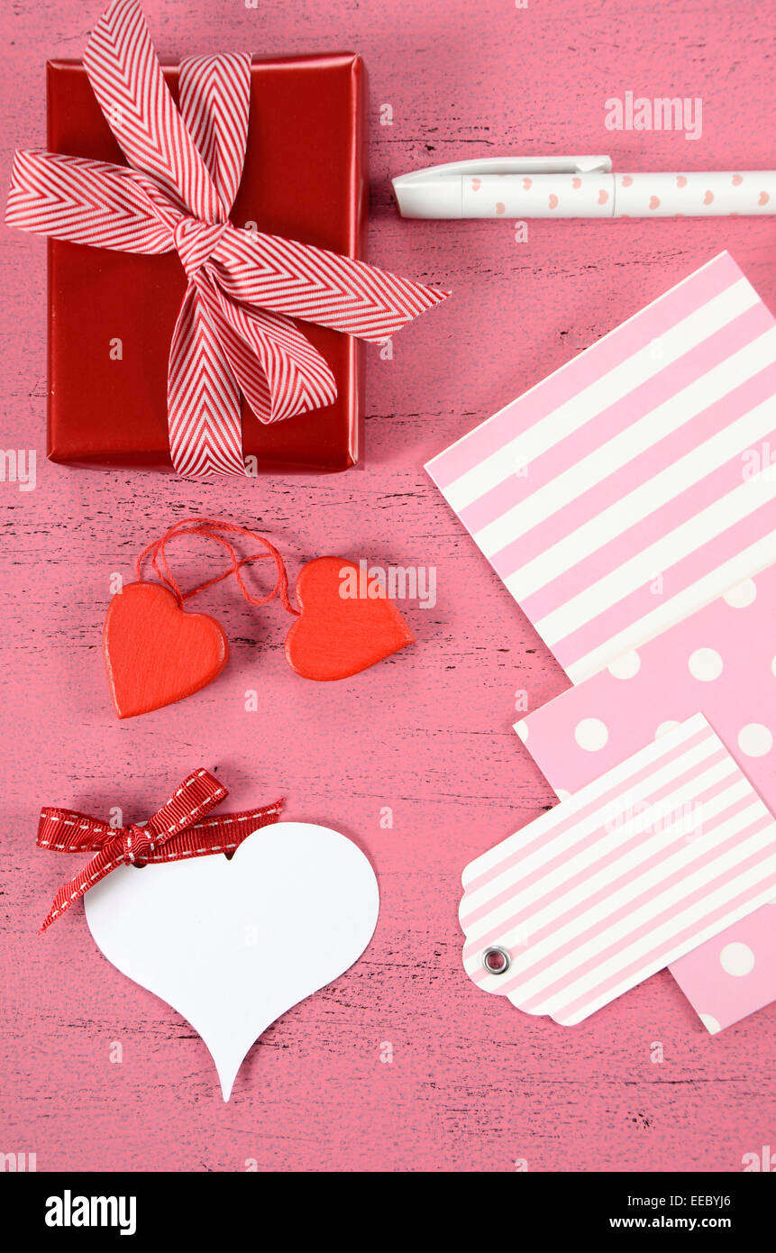 Happy Valentines Day Geschenke mit Geschenkanhänger und Herzen Verpacken auf shabby chic rosa Hintergrund - vertikale. Stockfoto