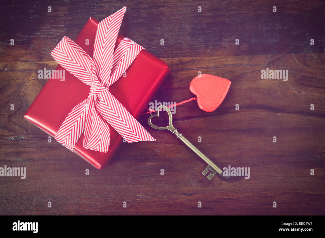 Retro-Vintage-Stil Happy Valentines Day Schlüssel zu meinem Herzen-Konzept mit großen hängenden Herzen auf dunklem Holz mit Geschenk. Stockfoto