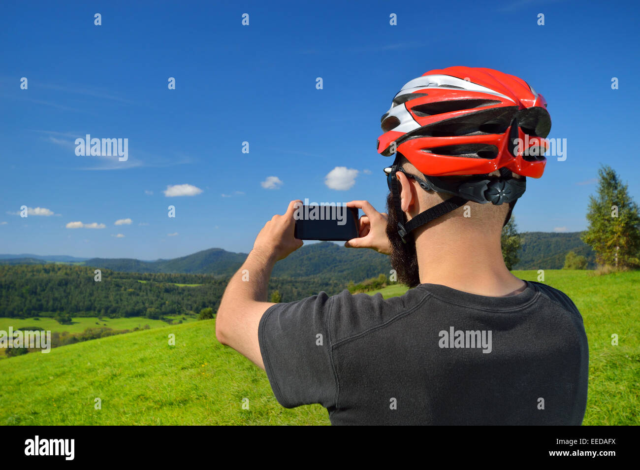 Radfahrer, die das Fotografieren mit Smartphone. Kaukasischen Mann in Fahrradhelm Smartphone Foto von Bergen. Outdoor-Aktivitäten. Stockfoto