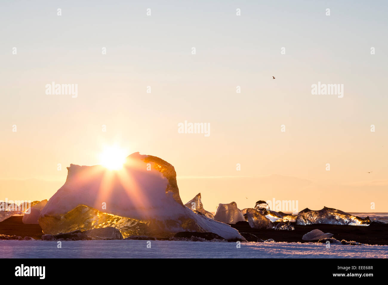 JÖKULSÁRLÓN, Island Sonne über der Oberseite von Natureis Bildhauerei an die Gletscherlagune im Süden Islands. Vögel im Hintergrund. Stockfoto