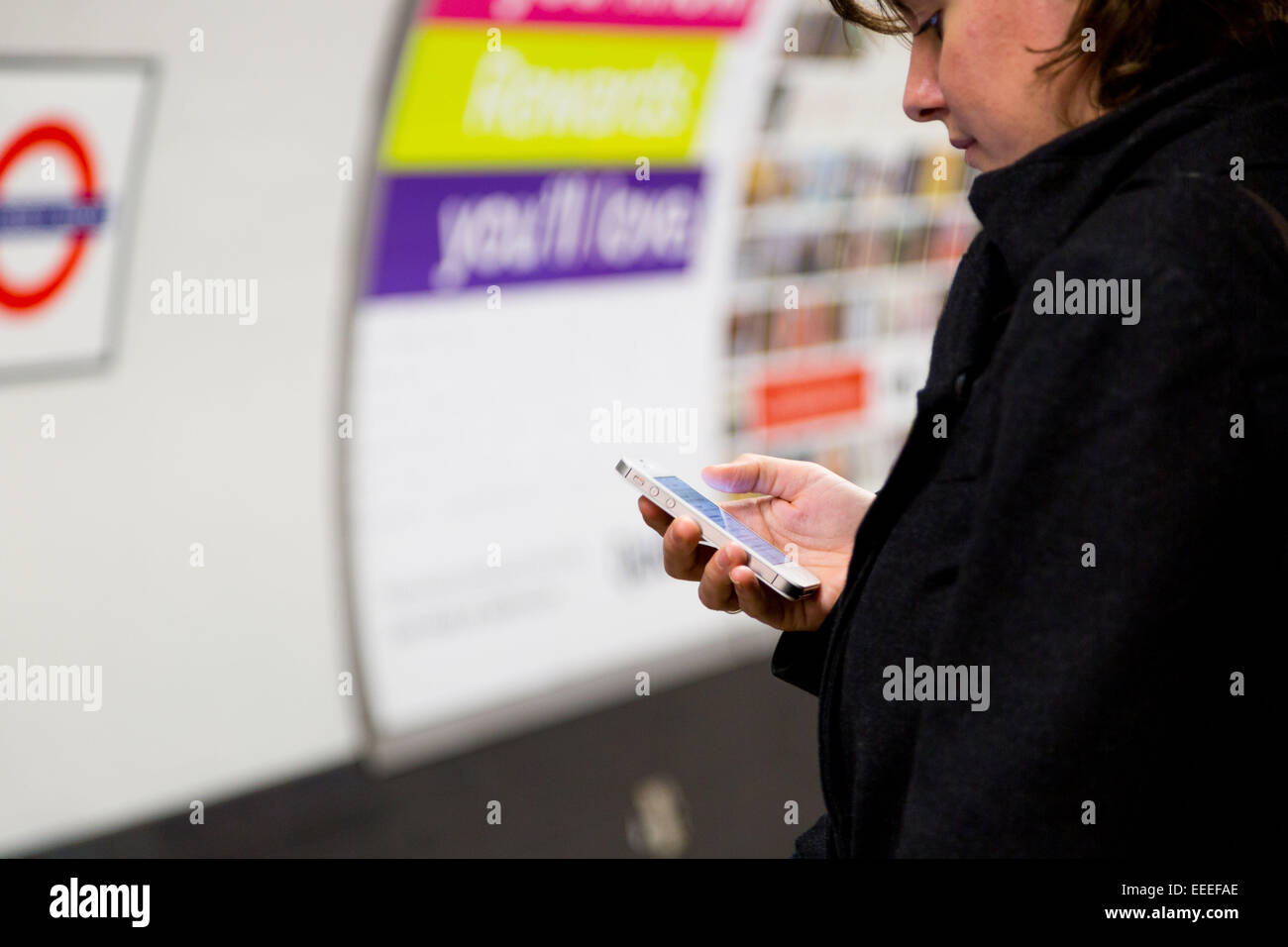 Pendler mit einem Smartphone auf einer unterirdischen Plattform Stockfoto