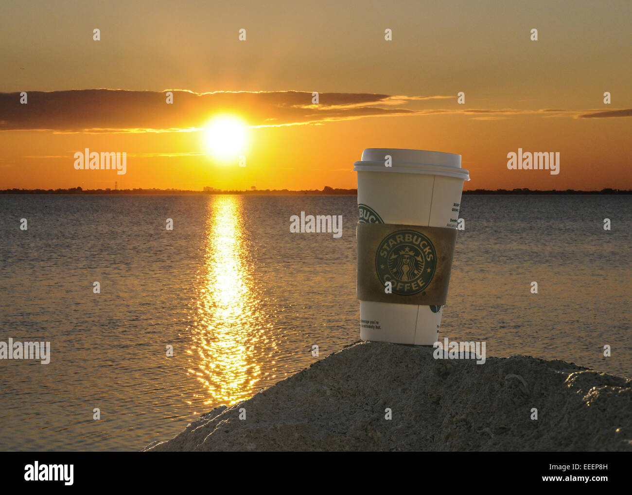 Starbucks Tasse auf einem Haufen Sand mit den Sonnenuntergang im Hintergrund über den intercoastal. Stockfoto