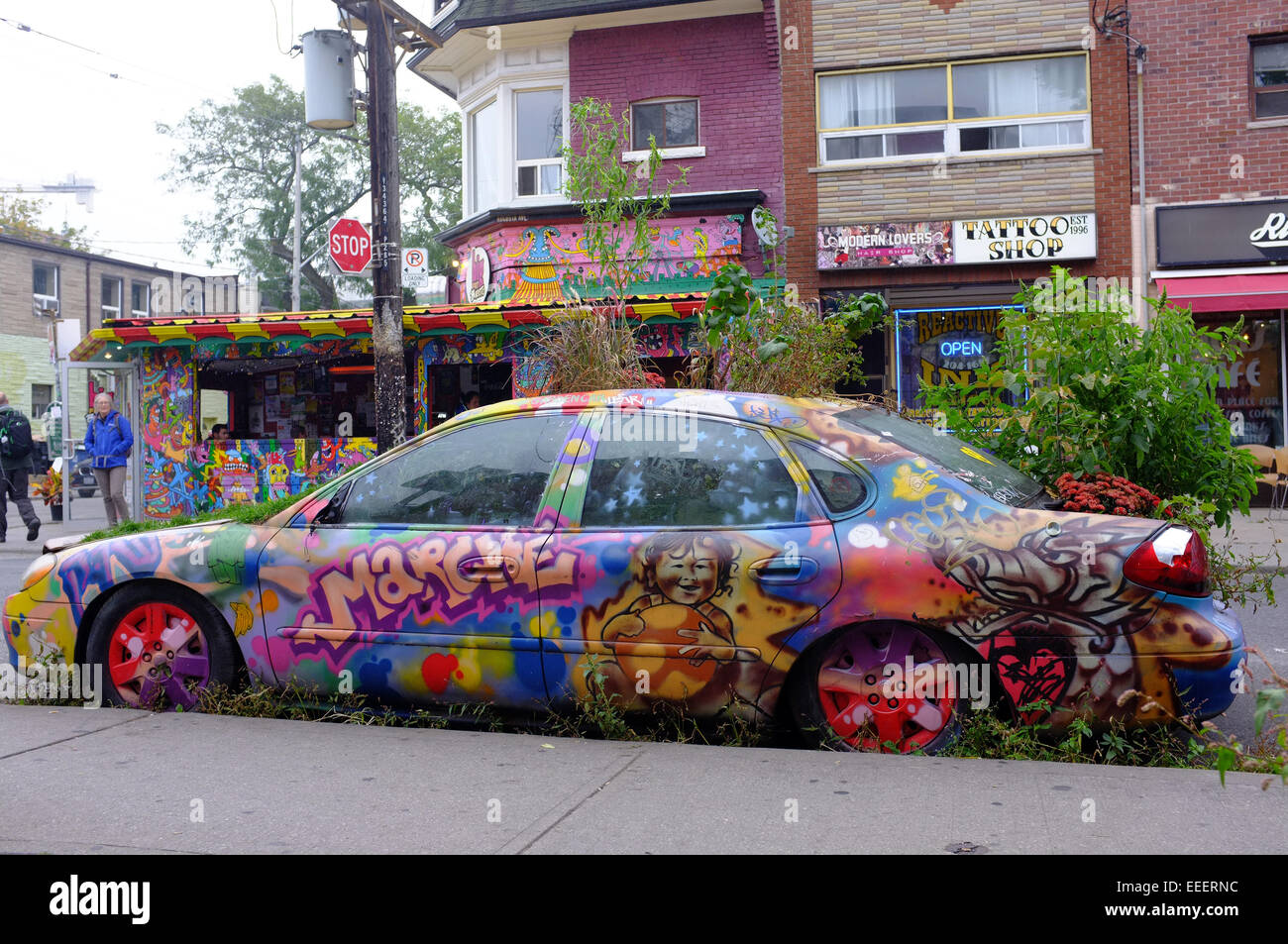 Ein Mietwagen in Kensington Market in Toronto bedeckt Graffiti und mit Pflanzen wachsen aus ihm heraus. Stockfoto