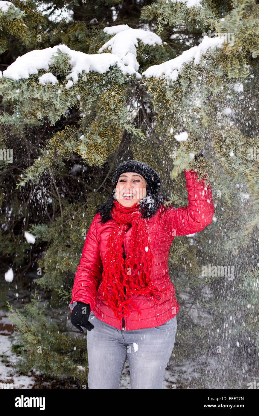Schwarzhaarige türkische Frauen stehen und spielen unter den schneebedeckten Zweigen Stockfoto