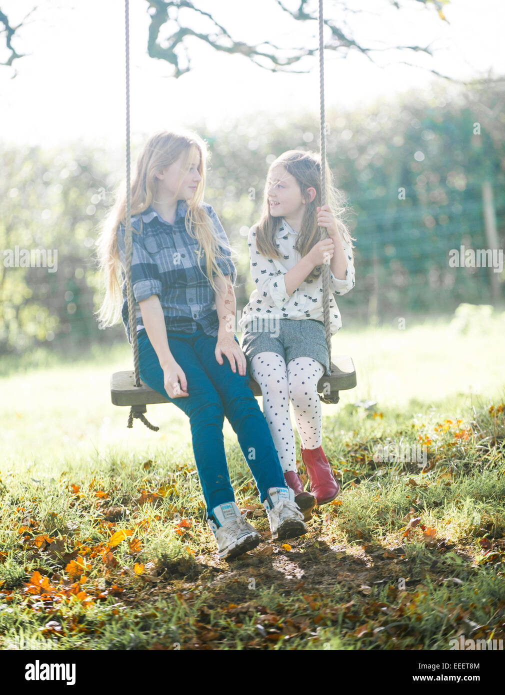 Zwei Mädchen saß auf einer Schaukel in der englischen Landschaft Stockfoto