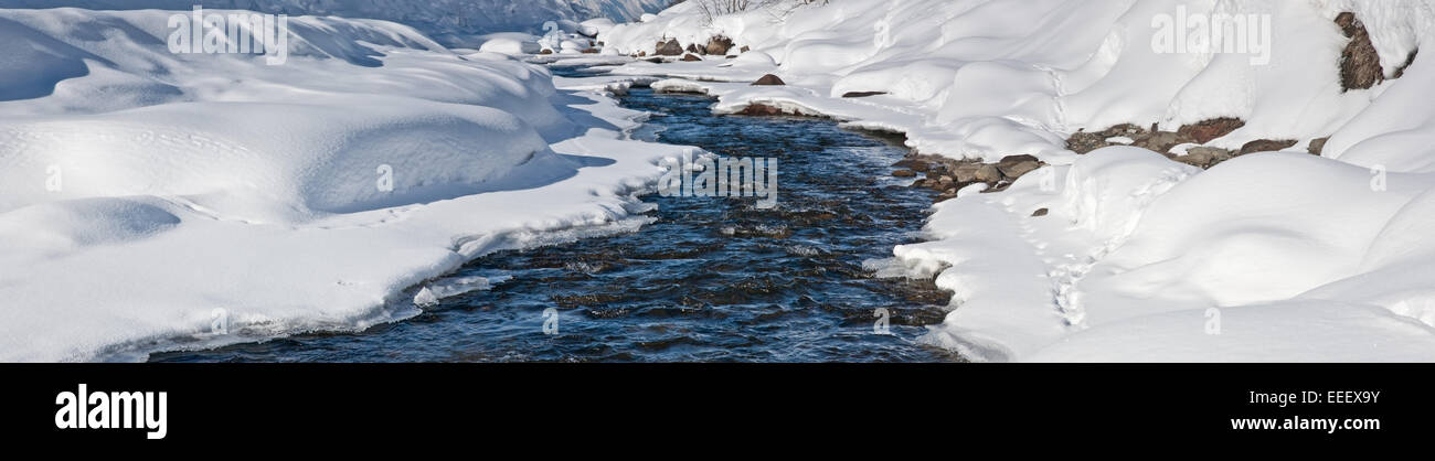 Dick Schnee beiderseits einer blauen Fluss Stockfoto