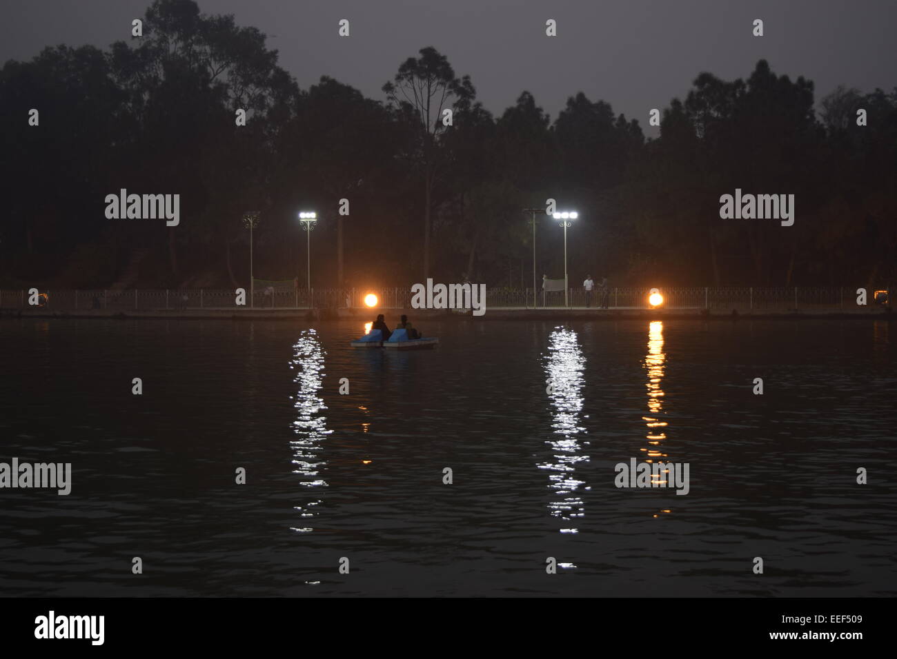 Bootfahren in der Nacht in einem künstlichen See in der Abenddämmerung. Stockfoto