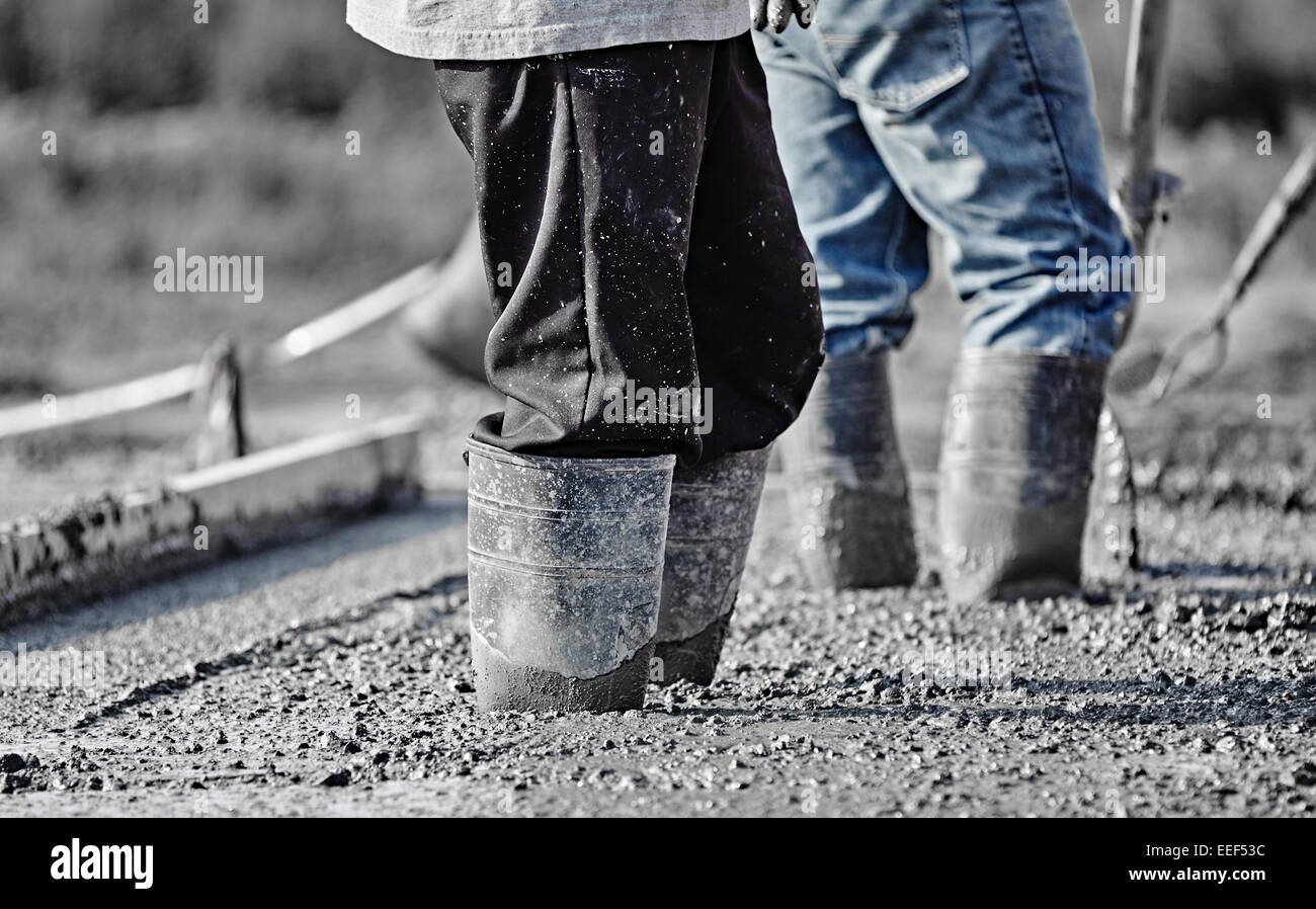 Nahaufnahme Bild von zwei Bauarbeiter stehen in frisch Beton mit hohen Gummistiefeln gegossen. Stockfoto
