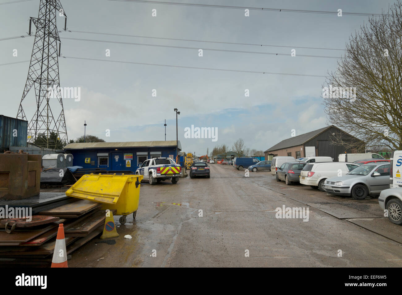 Gewerbegebiet auf einem dunklen Januartag im Vereinigten Königreich. Winterliche triste Szene mit schlammigen Betonstraße und industriellen Hallen. Stockfoto
