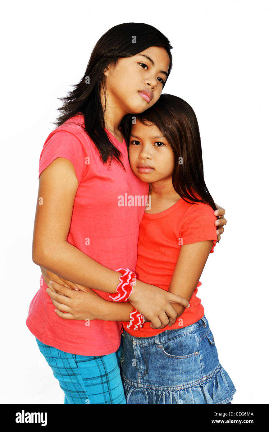 Ein Teenager-Mädchen, die versuchen, ihre jüngere Schwester mit einer Umarmung & traurigen Augen zu trösten! Stockfoto