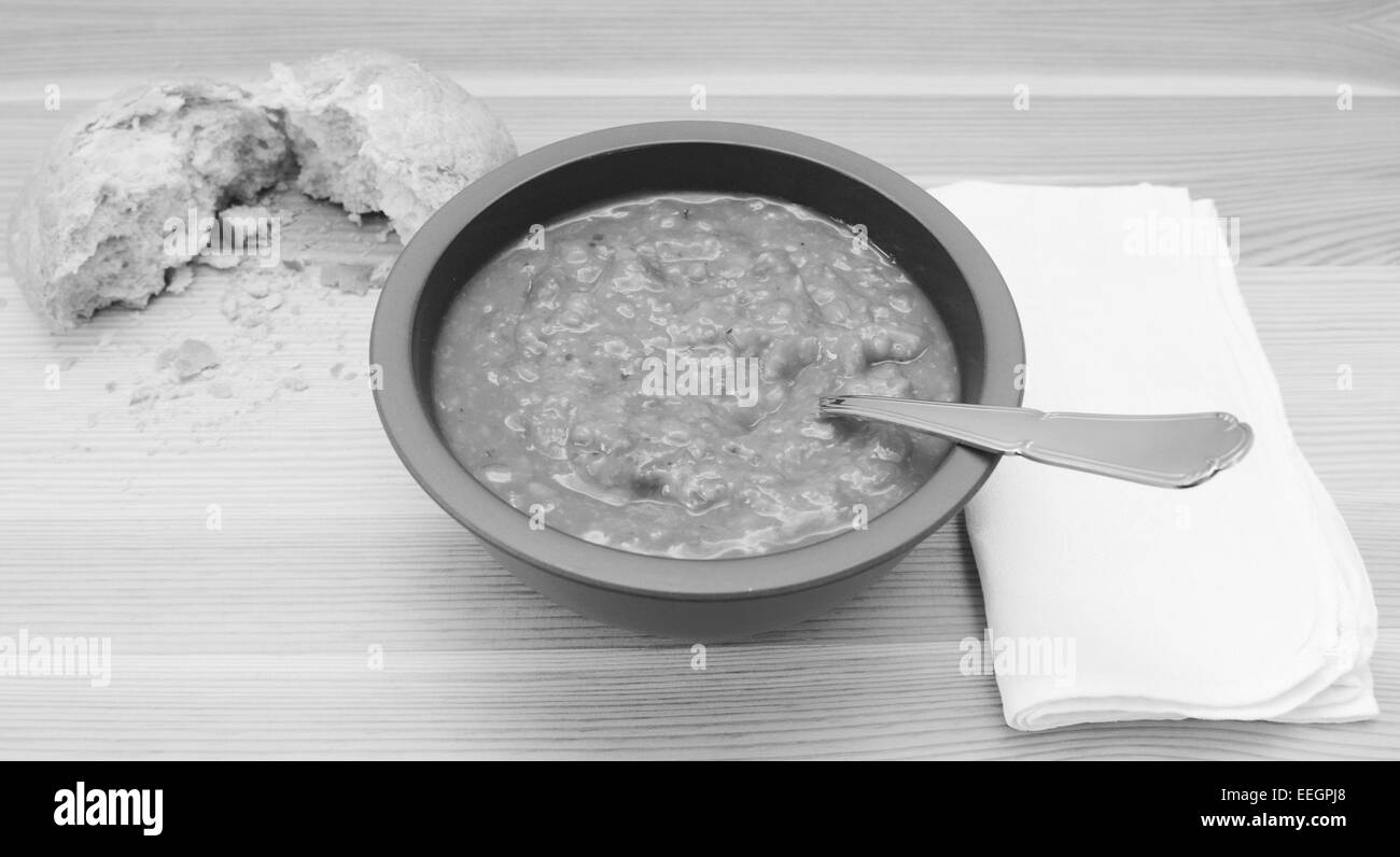 Tischdekoration für die Suppe mit einem zerrissenen Brötchen und weiße Serviette - monochrome Verarbeitung Stockfoto