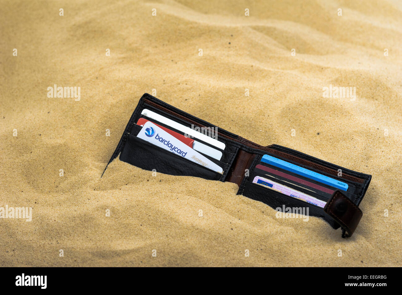 Brieftasche fallen gelassen und halb begraben an einem Sandstrand. Stockfoto