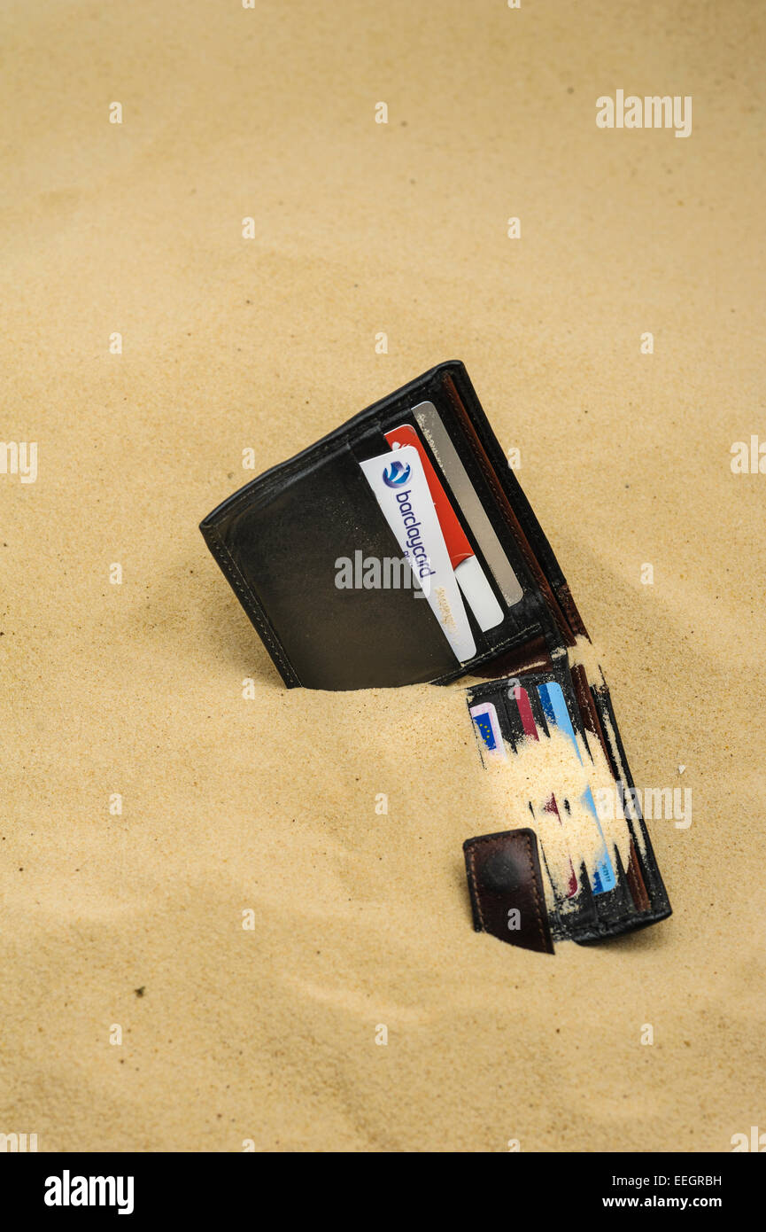 Brieftasche fallen gelassen und halb begraben an einem Sandstrand. Stockfoto