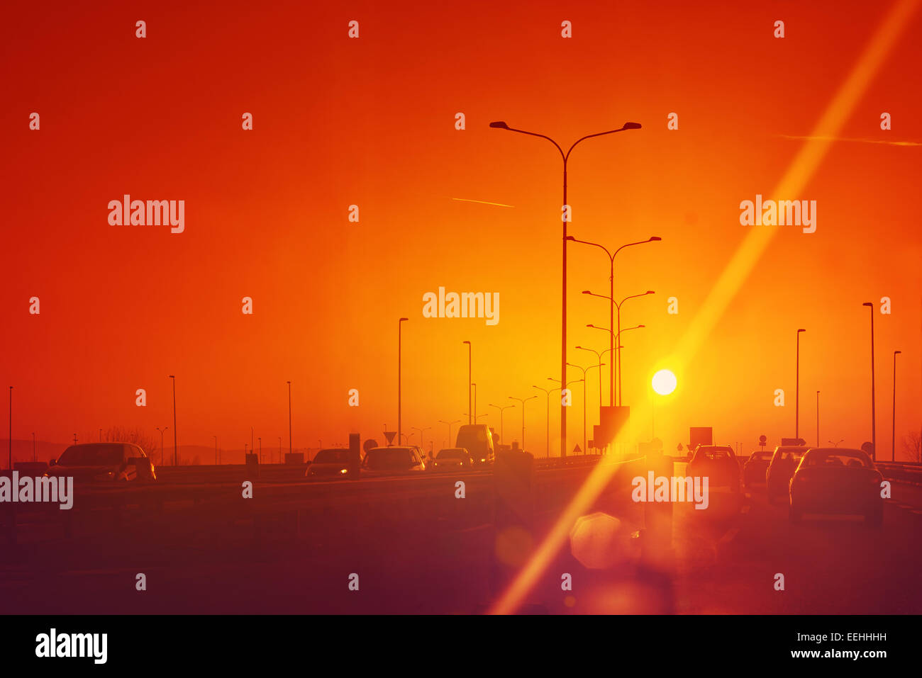 Stadtverkehr im Sonnenuntergang, Autos fahren auf der Fahrbahn, Toned Bild mit Sun Flare Stockfoto