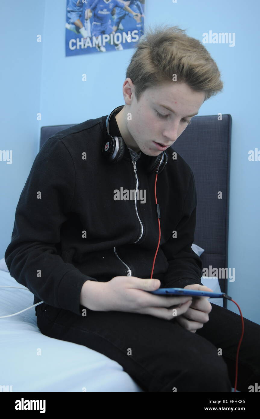 Teenage Boy Verwendung An Apple iPad Mini mit Beats Kopfhörer Stockfoto