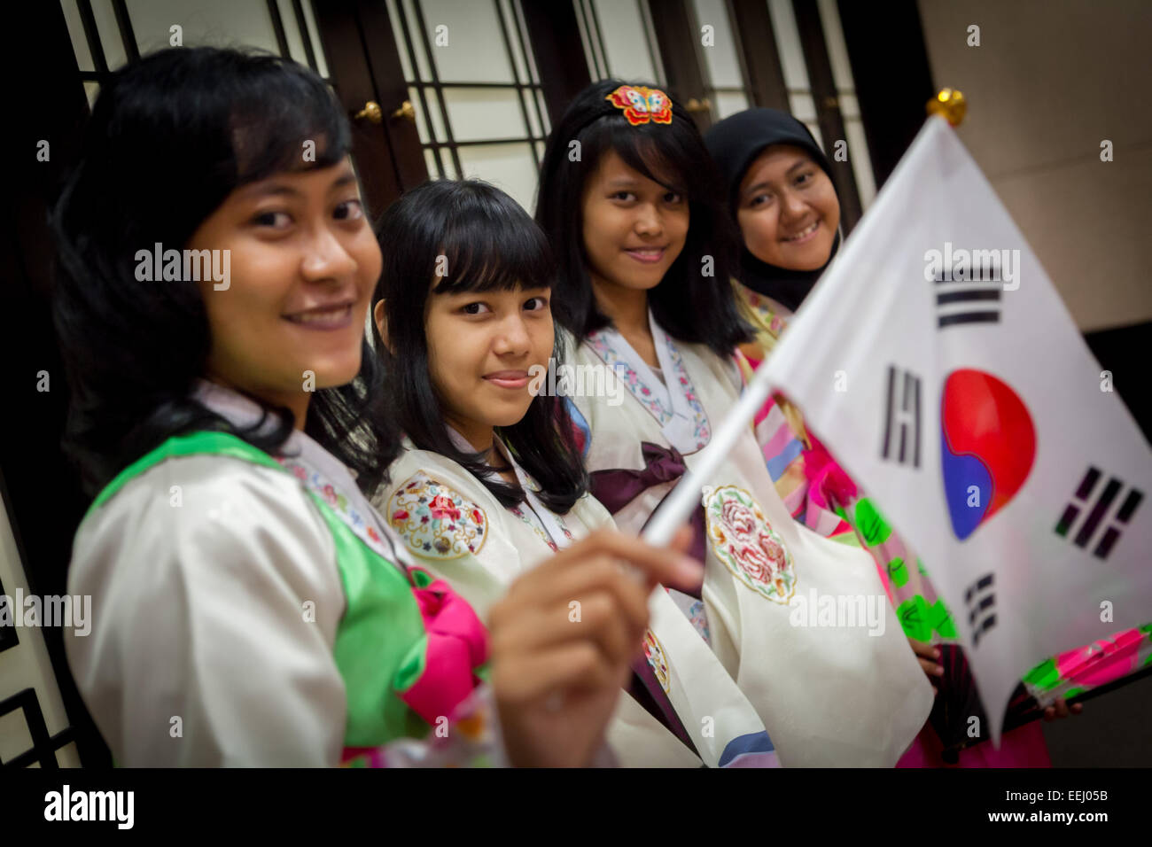 Indonesische Studenten tragen „hanbok“, traditionelle koreanische Kleidung, während sie im Korea Cultural Center in Jakarta, Indonesien, südkoreanische Flaggen halten. Stockfoto