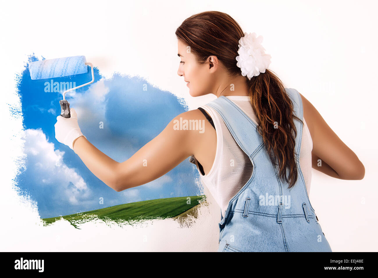 Junge Frau malt eine Naturlandschaft auf Wand mit Walze. Wandmalerei an Wand. Ökologe Stockfoto