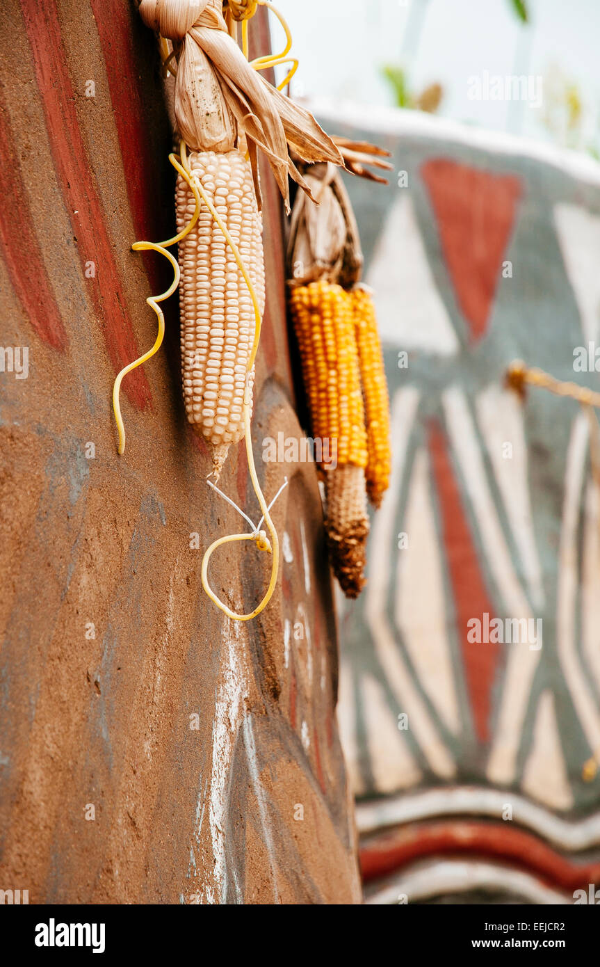 Mais, hängend von einem Kassena gemaltes Haus, Ghana Stockfoto