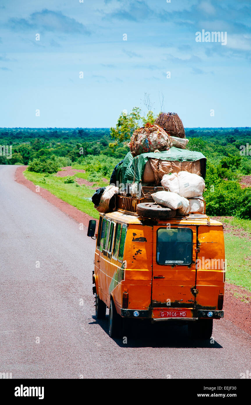 Van verwendet als öffentliche Verkehrsmittel stark geladen auf Dachgepäckträger auf einer Straßenkreuzung der grünen Savanne, Mali. Stockfoto