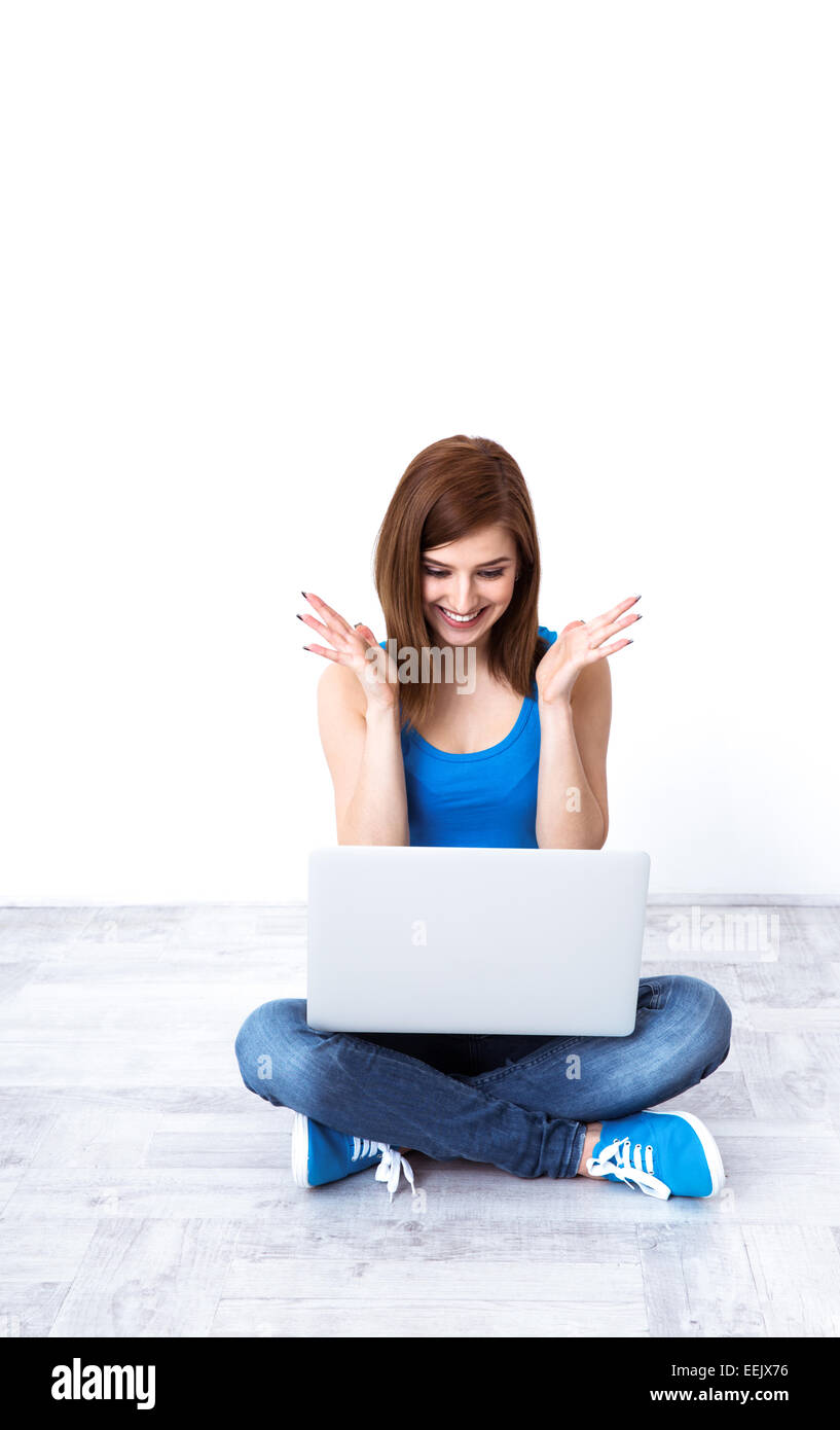 Glückliche Frau auf dem Boden sitzen und mit Blick auf laptop Stockfoto