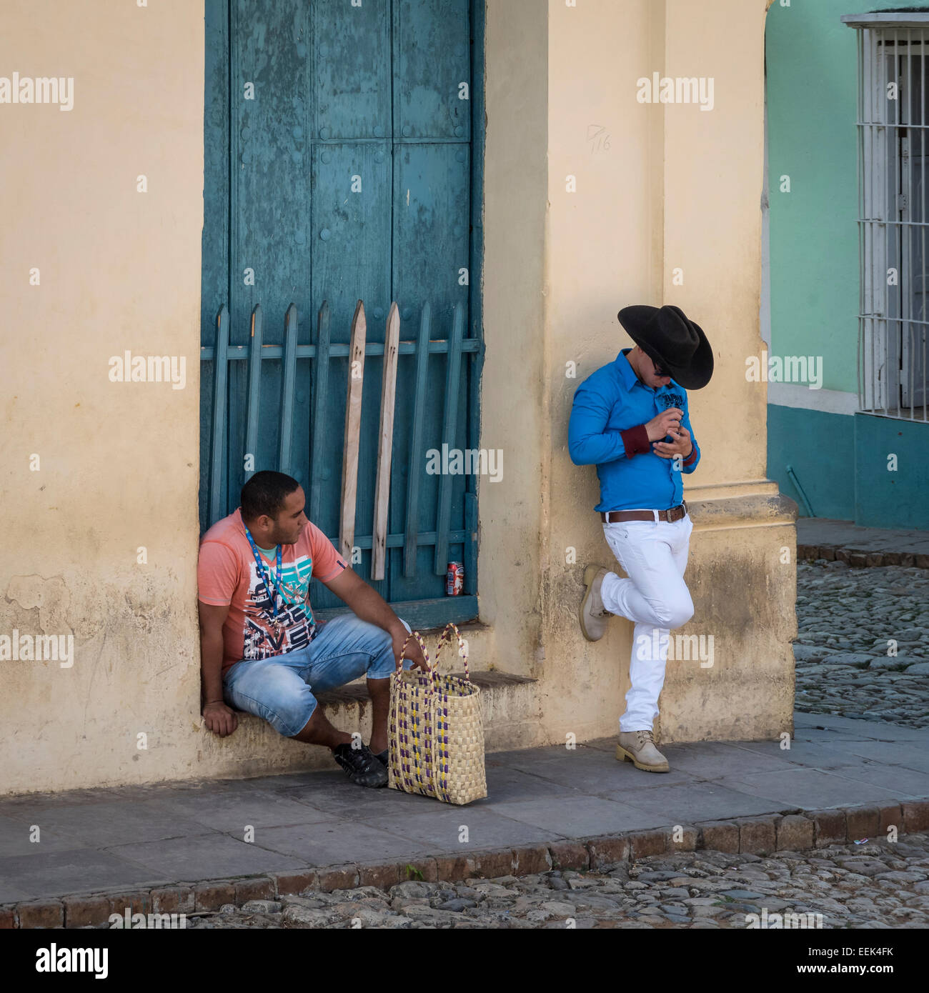 Zwei Männer an einer Straßenecke in Trinidad, Kuba. Man sitzt und ein Stand mit Hut auf. Stockfoto