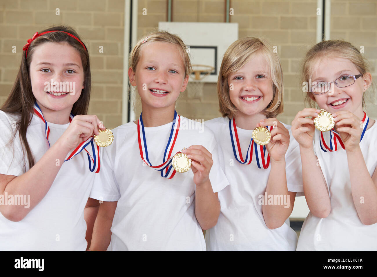 Weiblich-Schule Sportmannschaft In Turnhalle mit Medaillen Stockfoto