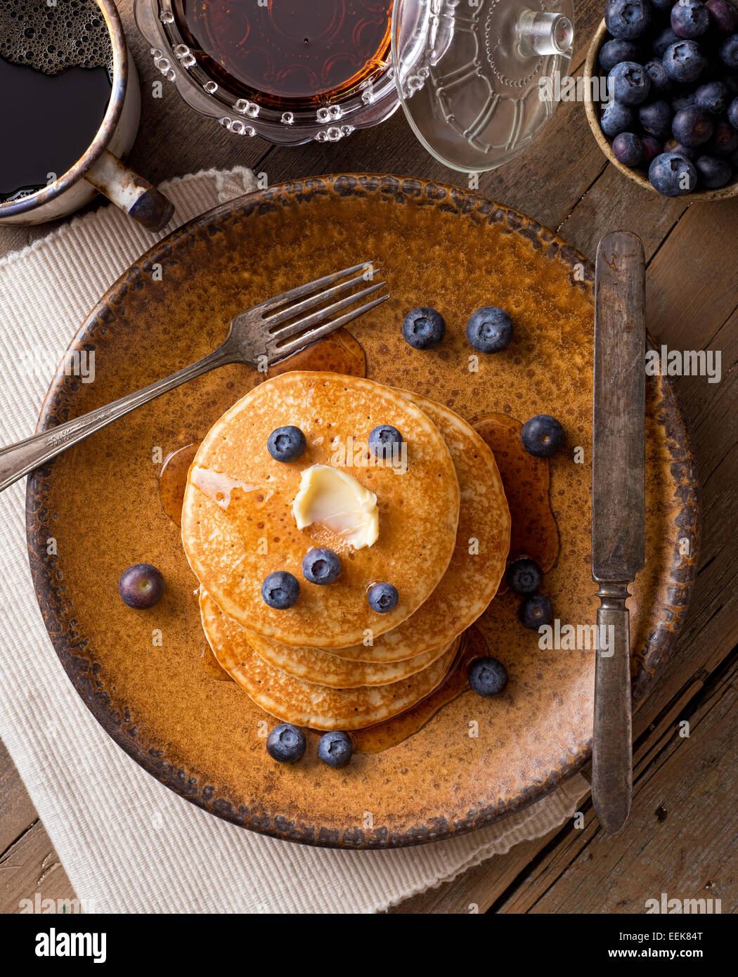 Pfannkuchen mit Blaubeeren und Ahornsirup auf einem rustikalen Tisch. Stockfoto