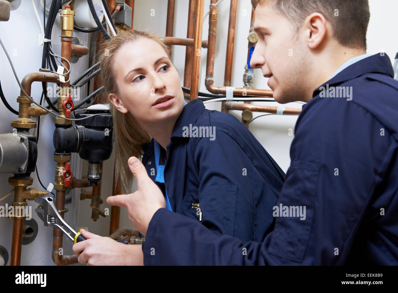 Weiblichen Auszubildenden Klempner Arbeiten an zentralen Heizkessel Stockfoto