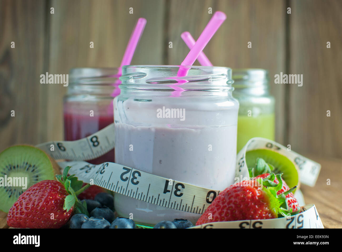 Aromatisierte Smoothies einschließlich Berry und Kiwi mit hölzernen Hintergrund mit Maßband Stockfoto