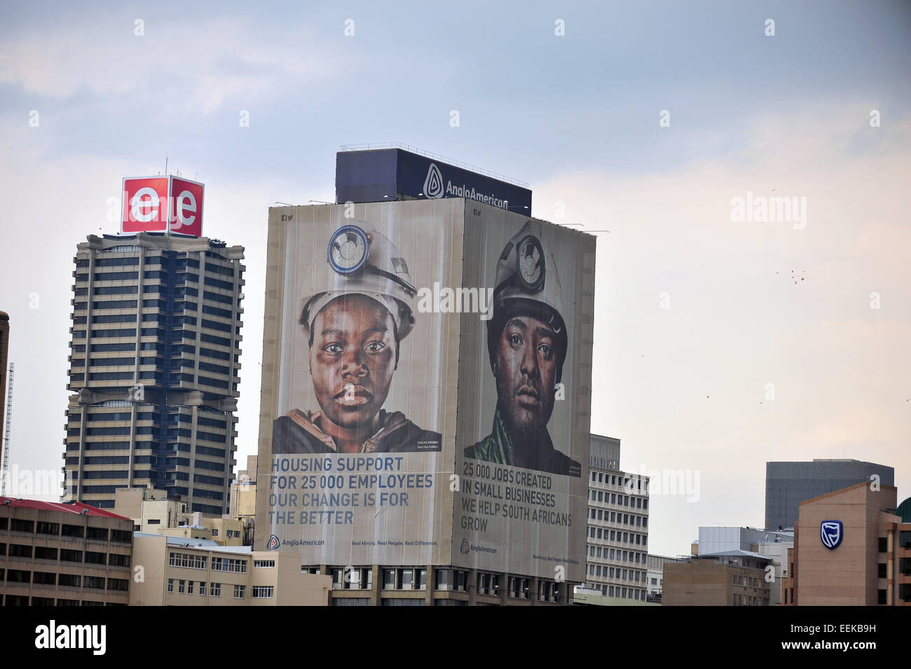 Die Gesichter der Bergleute auf einem Wolkenkratzer in der Innenstadt von Johannesburg betrachtet aus der Ferne. Stockfoto
