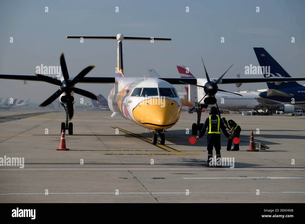 Ein Bombardier Dash 8 Flugzeug der NOK Air Low Cost Thai Airline wird von einem Wegweiser mit Handzeichen nach der Landung am Don Mueang Airport in der Stadt Bangkok Thailand einmarschiert Stockfoto