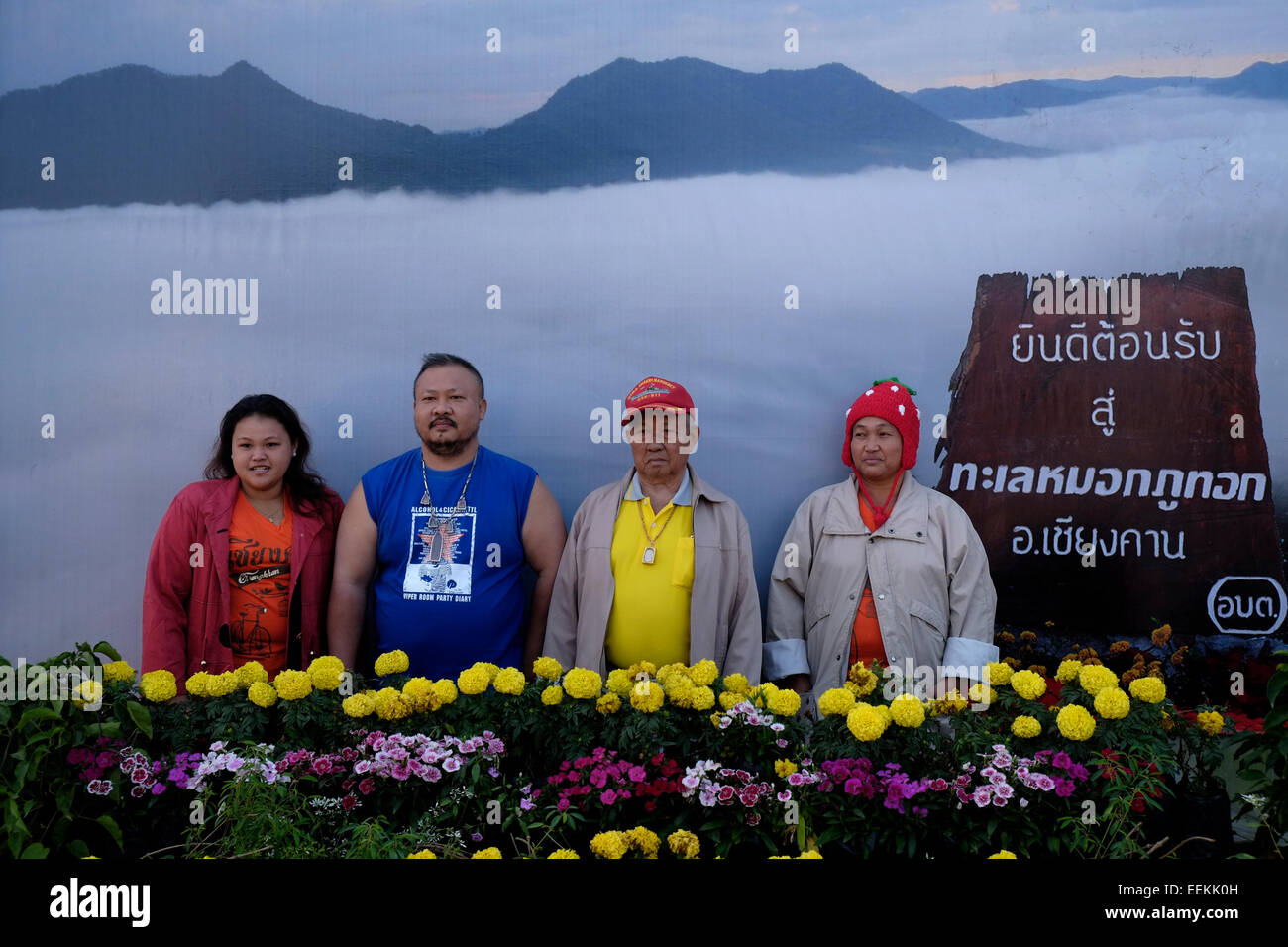 Lokale Thai Besucher vor großen Poster, Meer von Nebel an der Spitze von Phu Tok Berg in der Mitte von bueng Kan Provinz im nordöstlichen Ende des Isan, Nordosten Thailand posieren. Stockfoto