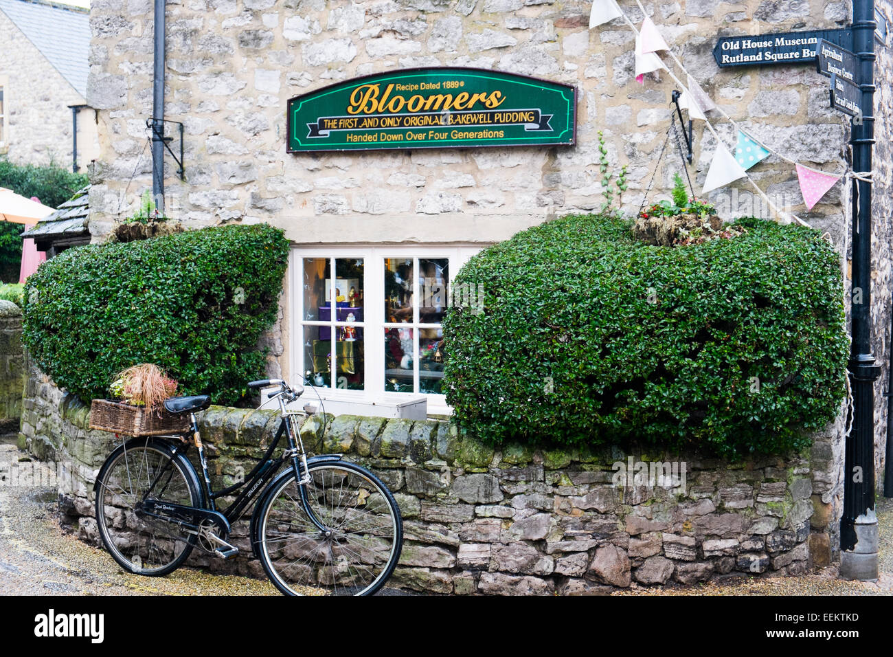 Bakewell, Derbyshire Dales, England, UK, Bloomers Original Bakewell Pudding Produzent im Stadtzentrum mit Oldtimer-Fahrrad parkt draußen Stockfoto