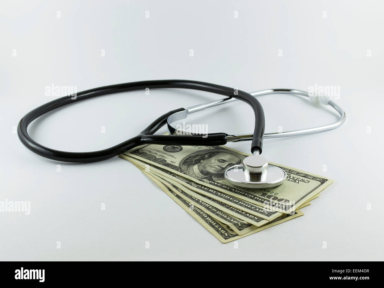 Medizinische Stethoskop über hundert-Dollar-Scheine illustrieren die Kosten des Gesundheitswesens auf weißem Hintergrund Stockfoto